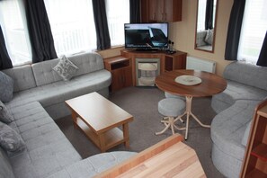Ein kompakter Wohnraum mit einer Couch, einem kleinen Tisch, einem Fernseher und einem Schrank.