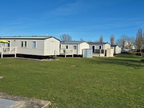 A row of mobile homes with a grassy yard and a clear blue sky. - 8 Berth Caravan at Butlins Skegness (Skegness)
