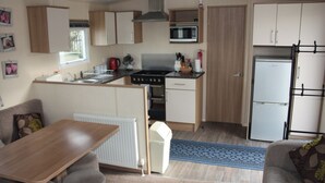 A compact kitchenette with a microwave, stove, and refrigerator. - 6 Berth Caravan Butlins Skegness Pet Friendly (Skegness)