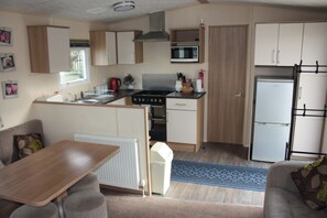 A compact kitchenette with a microwave, stove, and refrigerator. - 6 Berth Caravan Butlins Skegness Pet Friendly (Skegness)