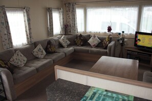 A living room with a sectional sofa, a coffee table, and a television on a stand. - 6 Berth Caravan Butlins Skegness Pet Friendly (Skegness)