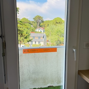 A door with a view of a residential area, a sign with text, and a power outlet on the wall. - Face mer à La Baule : Evobaule (La Baule-Escoublac)