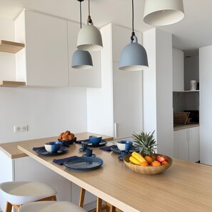 Eine moderne Küche mit einer Holzausziehtafel, hängenden Pendelleuchten und einer Obstschale.