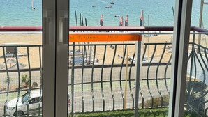A view of the sea from a balcony with a safety sign, a sandy beach, and parked cars. - Face mer à La Baule : Evobaule (La Baule-Escoublac)