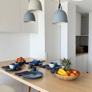 A modern kitchen with pendant lights, a wooden table, and a fruit bowl. - Face mer à La Baule : Evobaule (La Baule-Escoublac)