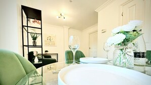 A dining area with a glass table, white plates, and a vase with white flowers. - Prime City of London Accommodation (London)