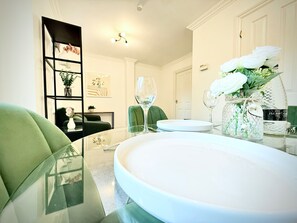 A dining area with a glass table, white plates, and a vase with white flowers. - Prime City of London Accommodation (London)
