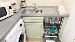 A compact kitchen with a washing machine, a dishwasher, and a sink. - Prime City of London Accommodation (London)