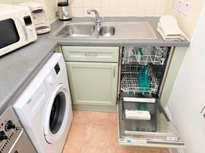 A compact kitchen with a washing machine, a dishwasher, and a sink. - Prime City of London Accommodation (London)