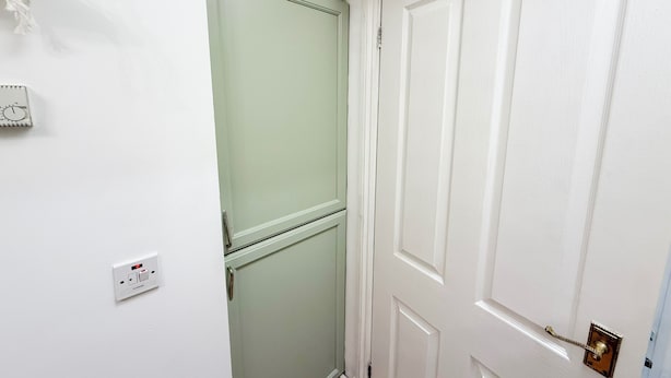 A white door with a brass handle, a light switch, and a thermostat on the wall. - Prime City of London Accommodation (London)
