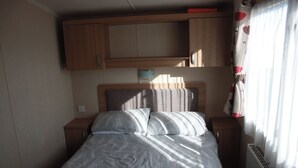 Een enkel bed met hoofdeinde, twee nachtkastjes en een raam met gordijnen.