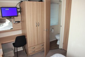 A bedroom with a wooden wardrobe, a desk with a computer monitor, a black chair, and a bathroom with a toilet and sink. - 8 Berth Caravan at Butlins Skegness Pet Friendly (Skegness)