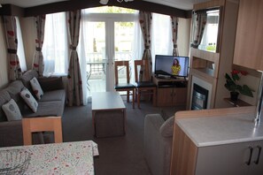 A compact living space with a sofa, a dining table, a TV, and a kitchenette. - 8 Berth Caravan at Butlins Skegness Pet Friendly (Skegness)