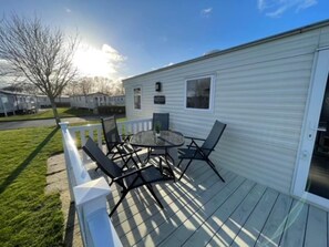 Ein Wohnmobil mit Terrasse, Gartenmöbeln und blauem Himmel.