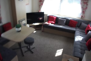 Een woonkamer met een bank, een televisie en een eettafel.