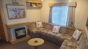 Ein Wohnzimmer mit einer Sofagarnitur, einem Kamin, einem Couchtisch und einem Gemälde an der Wand.