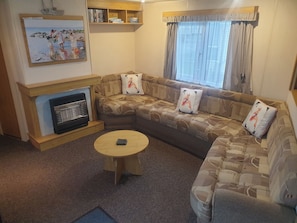 Ein Wohnzimmer mit einer Sofagarnitur, einem Kamin, einem Couchtisch und einem Gemälde an der Wand.