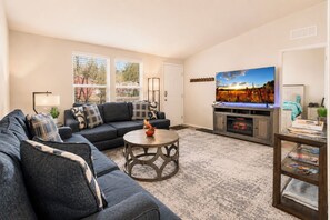 Una sala de estar con sofá, mesa de centro, televisor y chimenea.