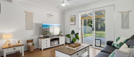 Ein Wohnzimmer mit Fernseher, Couchtisch, Sofa und Deckenventilator.