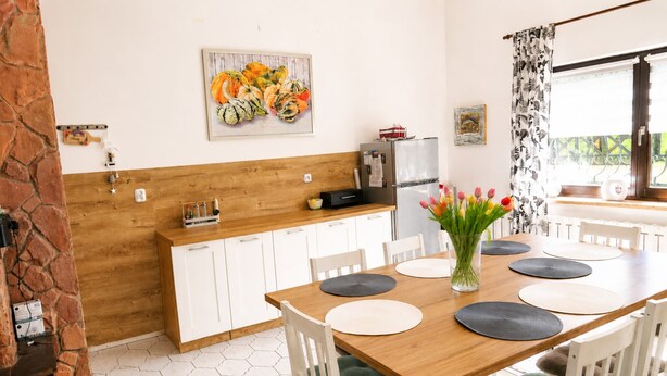 A kitchen with white cabinets, a wooden countertop, a refrigerator, and a dining table with chairs. - Holiday Home for 7 People Mrzezyno (Trzebiatow)