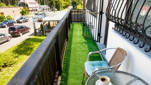 A balcony with a green artificial turf, a wicker chair, and a table with two cups of coffee. - Holiday Home for 7 People Mrzezyno (Trzebiatow)