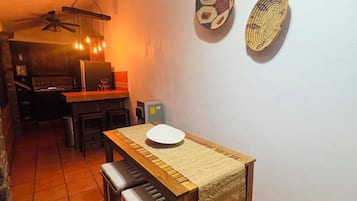 A dining area with a wooden table and chairs, a ceiling fan, and a wall-mounted light fixture.