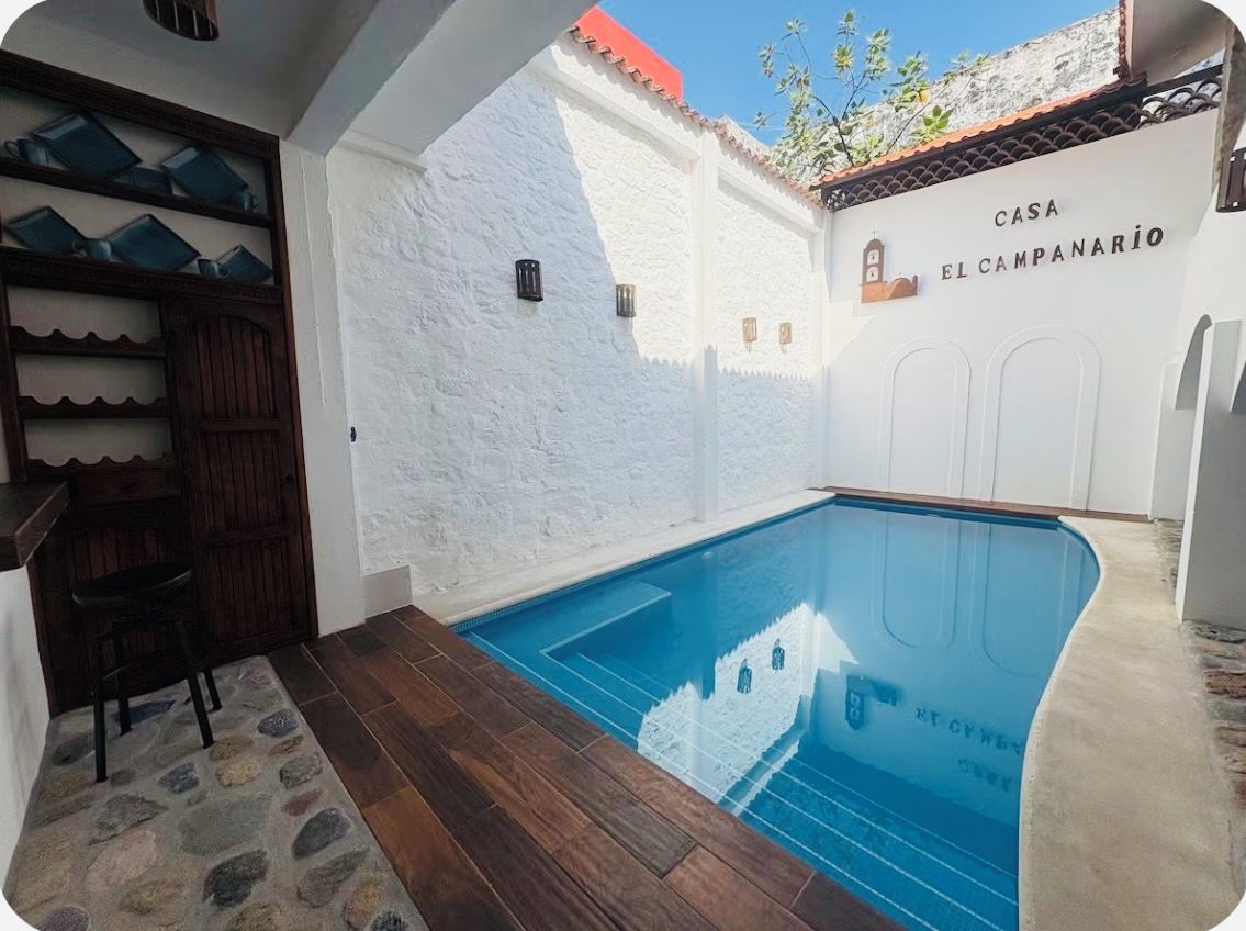 Ein Schwimmbecken mit einer weißen Wand und einer Tür mit der Aufschrift 'CASA EL CAMPANARIO'.