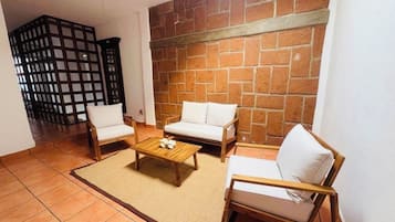 A living room with a brick wall, two white sofas, a wooden coffee table, and a ceiling fan.