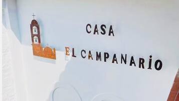 Un letrero con la inscripción 'CASA EL CAMPANARIO' e ilustración de un campanario.