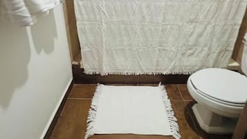 Un baño con cortina de ducha, una toalla blanca y un tapete en el suelo.