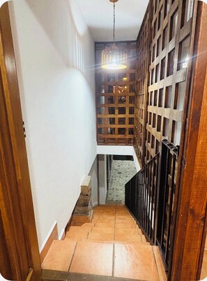 A narrow staircase with a wooden railing, a stone floor, and a hanging light fixture. - Alberca, Descanso, Encanto, Calidez y Tradición. Mascotas son Bienvenidas.  (Miacatlán)