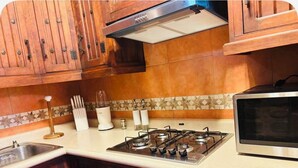 A kitchen with wooden cabinets, a gas stove, a microwave, and a tiled backsplash.