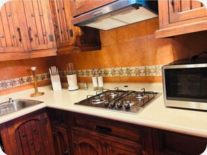 A kitchen with wooden cabinets, a gas stove, a microwave, and a tiled backsplash.