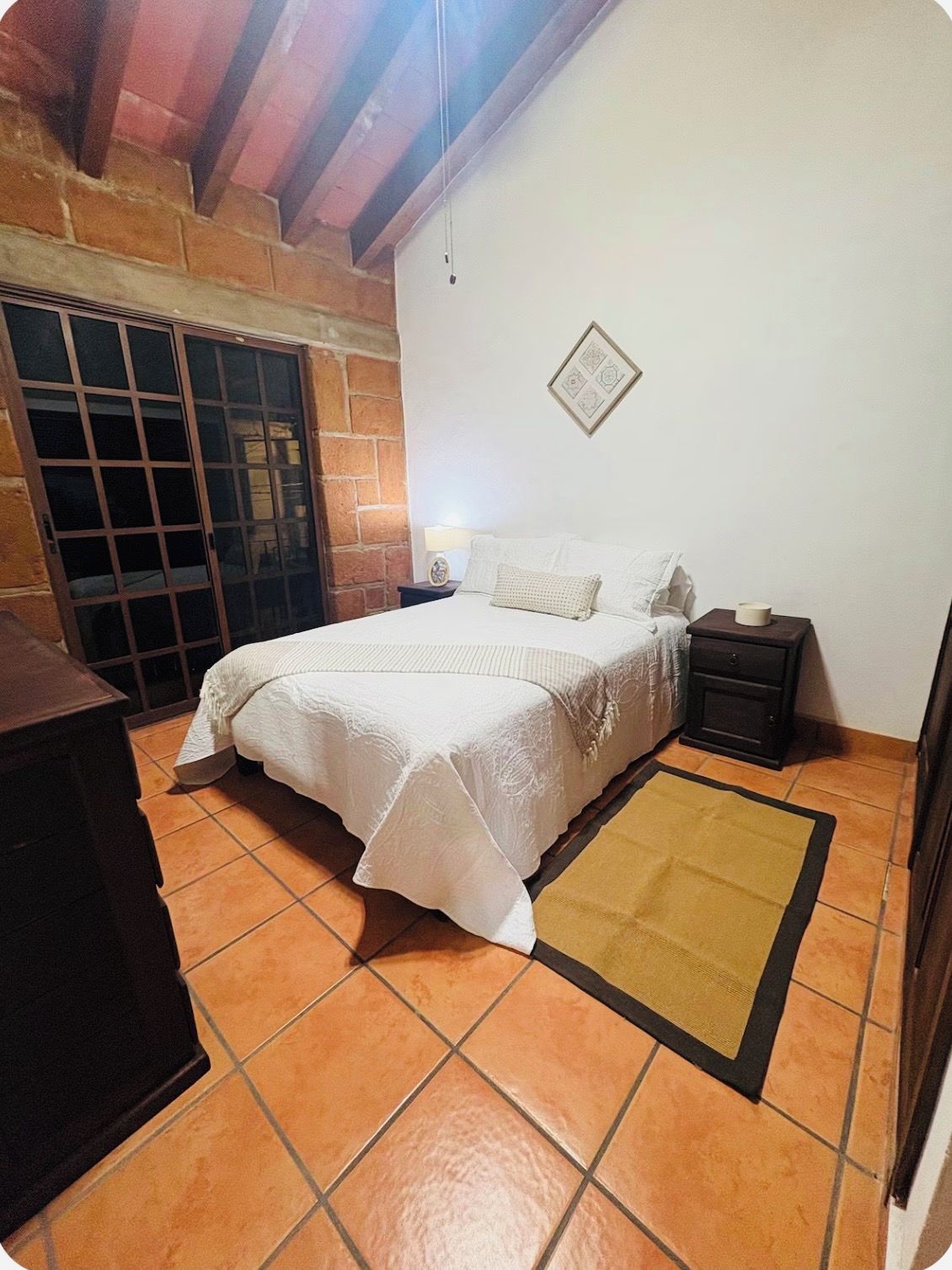 Ein Schlafzimmer mit einem Bett, Nachttischen, einem Teppich und einer Wandleuchte.