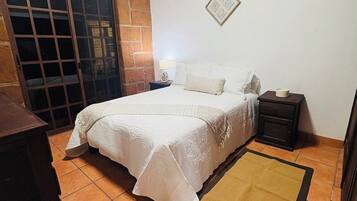 Ein Schlafzimmer mit einem Bett, Nachttischen, einem Teppich und einer Wandleuchte.