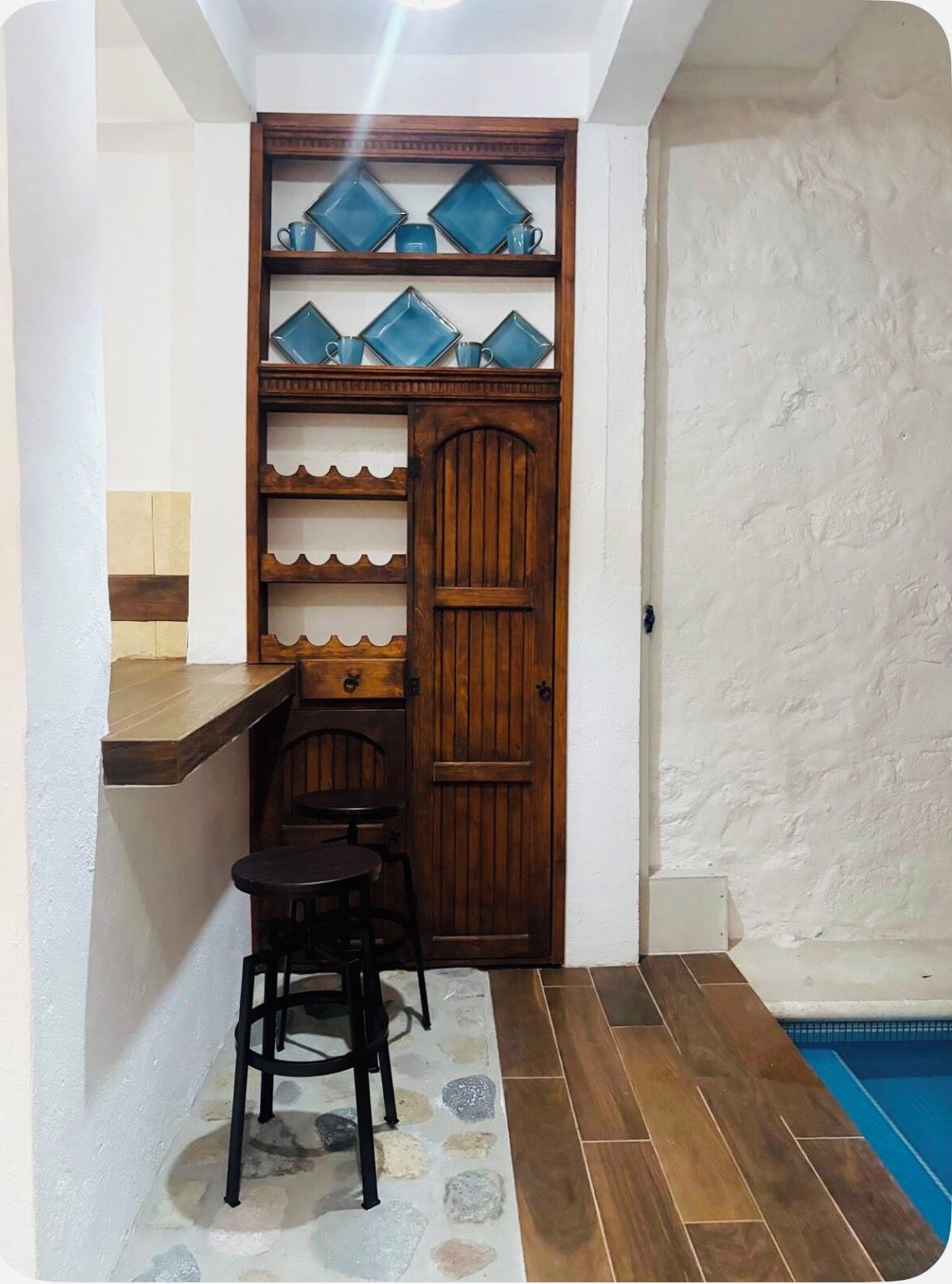 A compact room with a wooden door, a small table, two chairs, and a tiled floor.