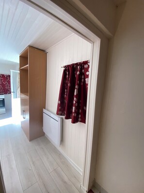 Una habitació amb un armari de fusta, un radiador i una cortina amb dibuixos.