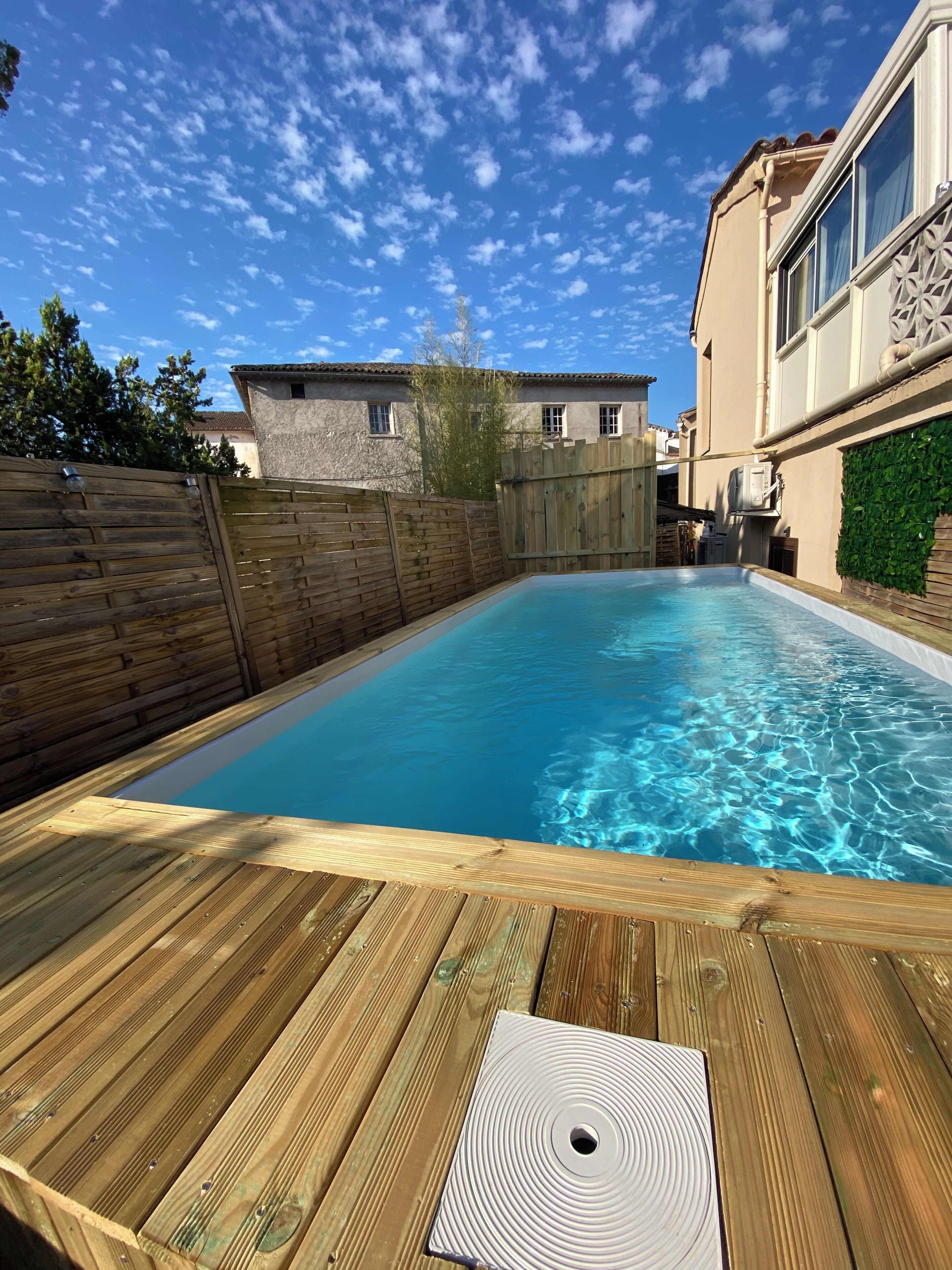A swimming pool with a wooden deck in a residential setting.