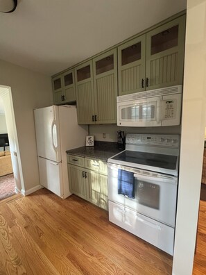 Una cocina con refrigerador, microondas, horno y armarios de madera.