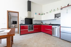 A modern kitchen with red cabinetry, stainless steel appliances, and a black range hood. - Villa Sa Xabola - Three Bedroom Villa, Sleeps 6 (Can Tabou)