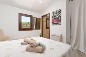 Ein Schlafzimmer mit Bett, Fenster, Spiegel, Heizkörper und Tür.