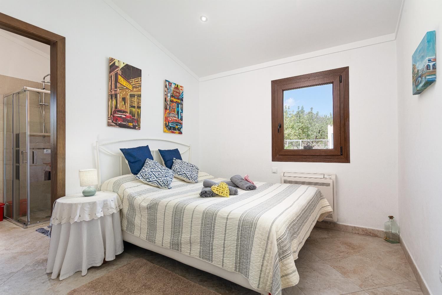 A bedroom with a bed, a bedside table, a window, and a door.