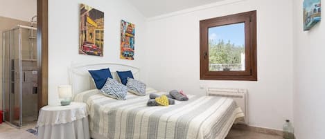 A bedroom with a bed, a bedside table, a window, and a door.