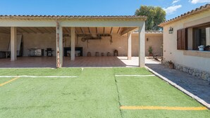 A covered outdoor area with artificial turf, a patio, and a building with a tiled roof. - Villa Sa Xabola - Three Bedroom Villa, Sleeps 6 (Can Tabou)