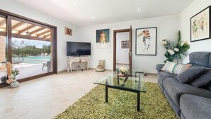 A modern living room with a glass coffee table, a grey sofa, and a television. - Villa Sa Xabola - Three Bedroom Villa, Sleeps 6 (Can Tabou)