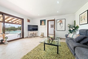 A modern living room with a glass coffee table, a grey sofa, and a television. - Villa Sa Xabola - Three Bedroom Villa, Sleeps 6 (Can Tabou)