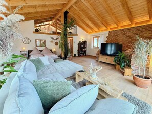 A spacious living room with a high ceiling, a fireplace, and a television. - Loft with lily pond and mountain pastures (Hausham)