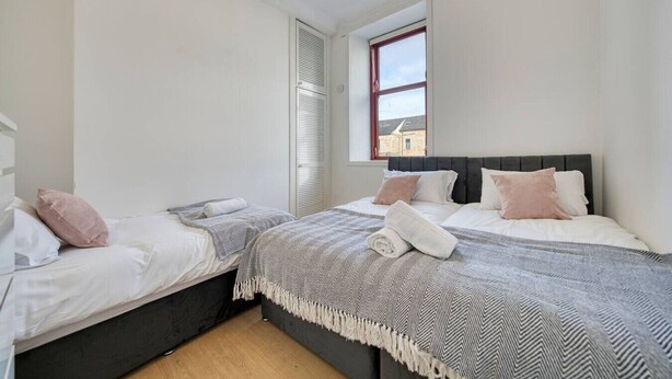 Een slaapkamer met twee bedden, een raam en een deur.