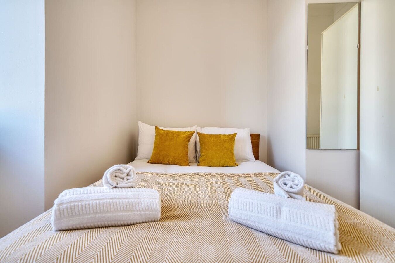 A hotel room with a bed, two pillows, and two towels.