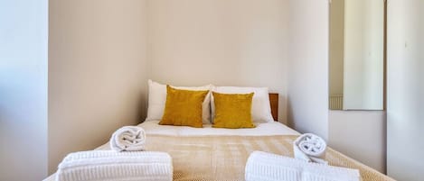 A hotel room with a bed, two pillows, and two towels.